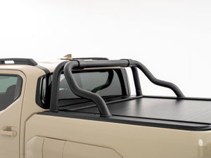 Close-up view of a Kia Tasman tub showing the HSP Roll R electric roller cover closed, with black tubular sports bars mounted above the cover behind the cab.