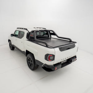 Angled 3/4 rear view of a white Kia Tasman fitted with an HSP Roll R electric roller cover in the closed position with black sports bars mounted.