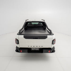 Straight rear view of a Kia Tasman fitted with the HSP Roll R electric roller cover, showing the closed aluminium roller shutter and integrated rear handle above the tailgate.